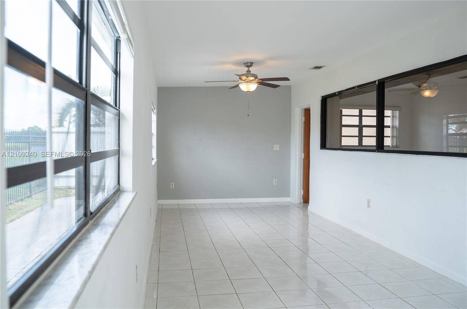 21115 SW 125th Ct Road, Miami, Miami, FL 33177 Ceramic tile flooring, expansive multi-pane windows, interior horizontal window pass-through with dark trim, and a ceiling-mounted light fixture with fan