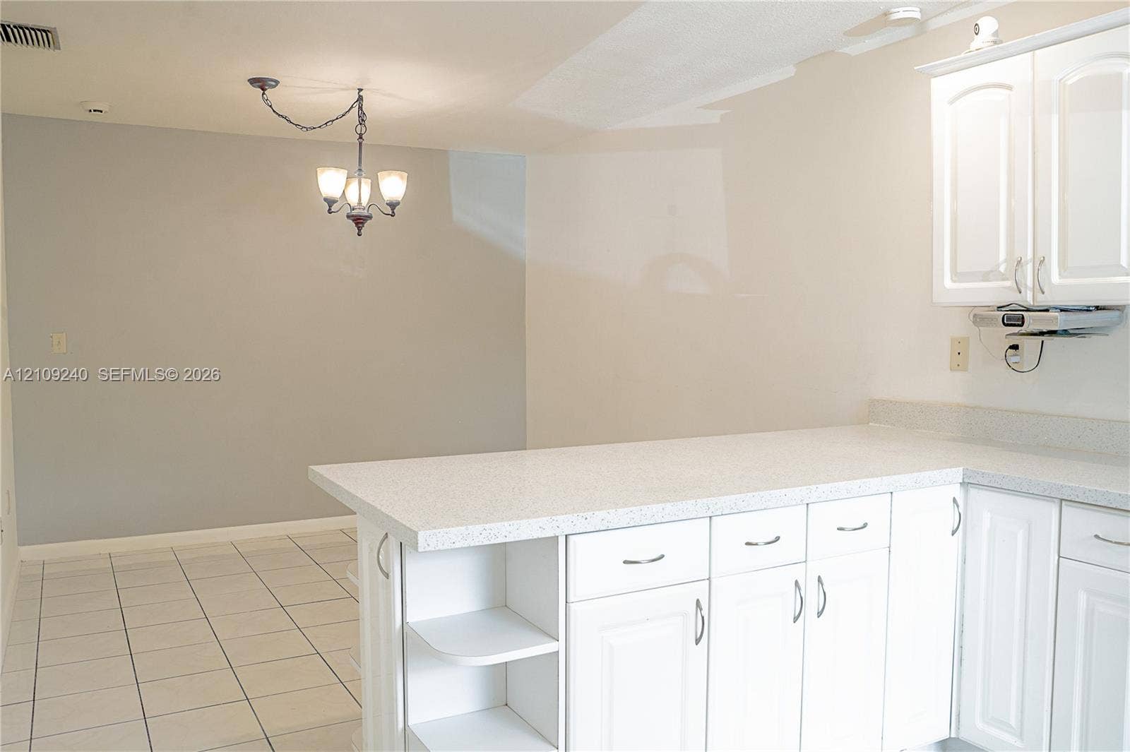 21115 SW 125th Ct Road, Miami, Miami, FL 33177 White cabinetry with integrated shelving, stone-finish countertops, tile flooring, and a multi-light chandelier