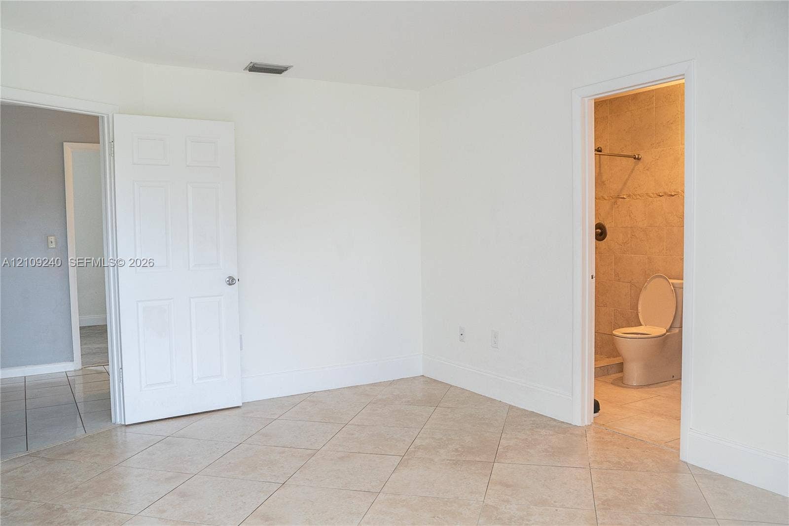 21115 SW 125th Ct Road, Miami, Miami, FL 33177 Interior space featuring neutral tile flooring, white-paneled interior doors, and a bathroom containing a tiled shower enclosure and ceramic toilet