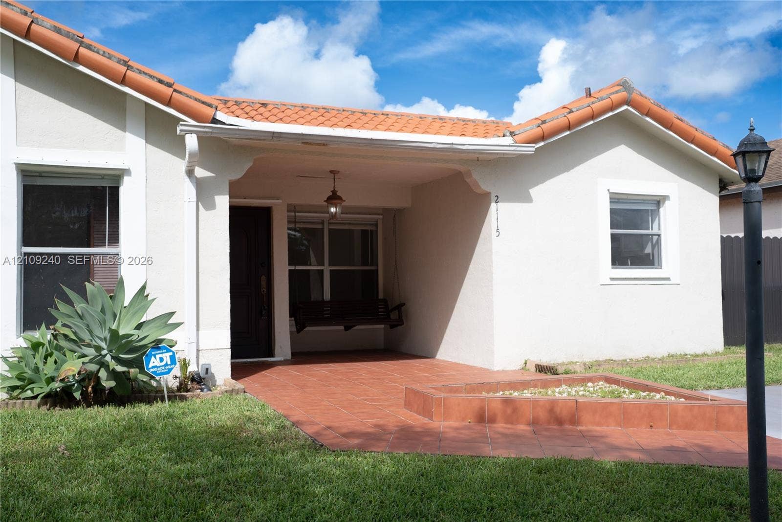 21115 SW 125th Ct Road, Miami, Miami, FL 33177 Stucco exterior featuring a clay tile roof, covered front porch with tiled flooring, and a raised exterior planter