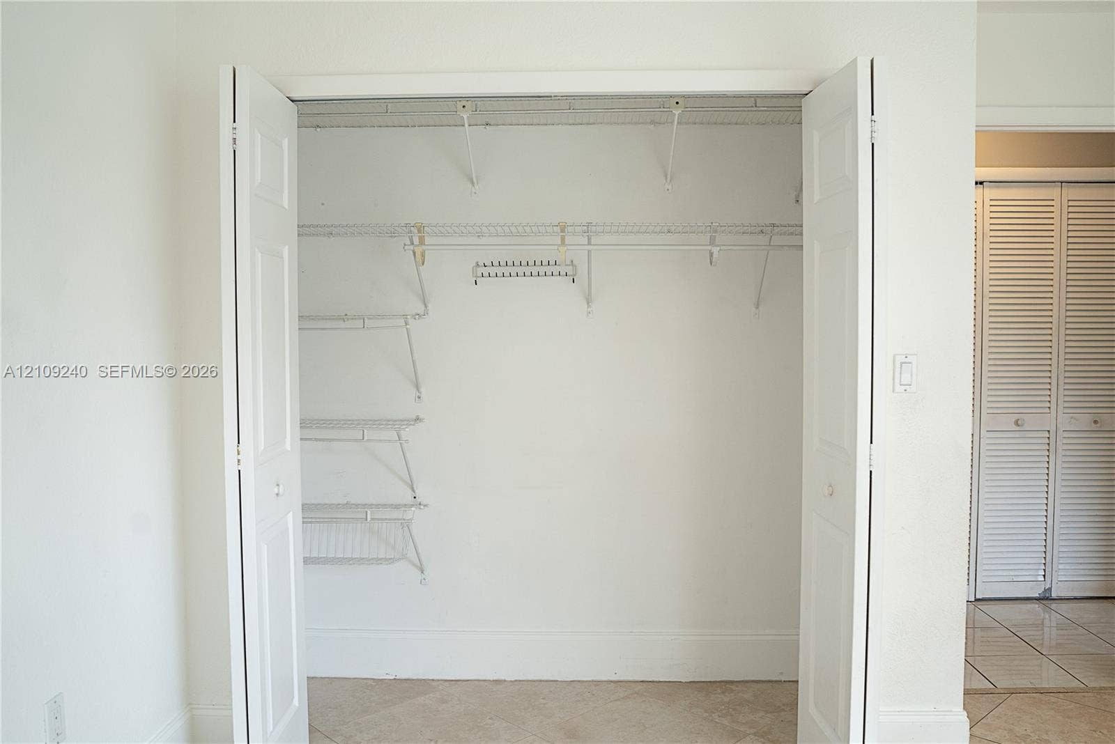 21115 SW 125th Ct Road, Miami, Miami, FL 33177 Reach-in closet featuring dual bifold doors, white wire shelving, integrated hanging rods, and an overhead storage shelf