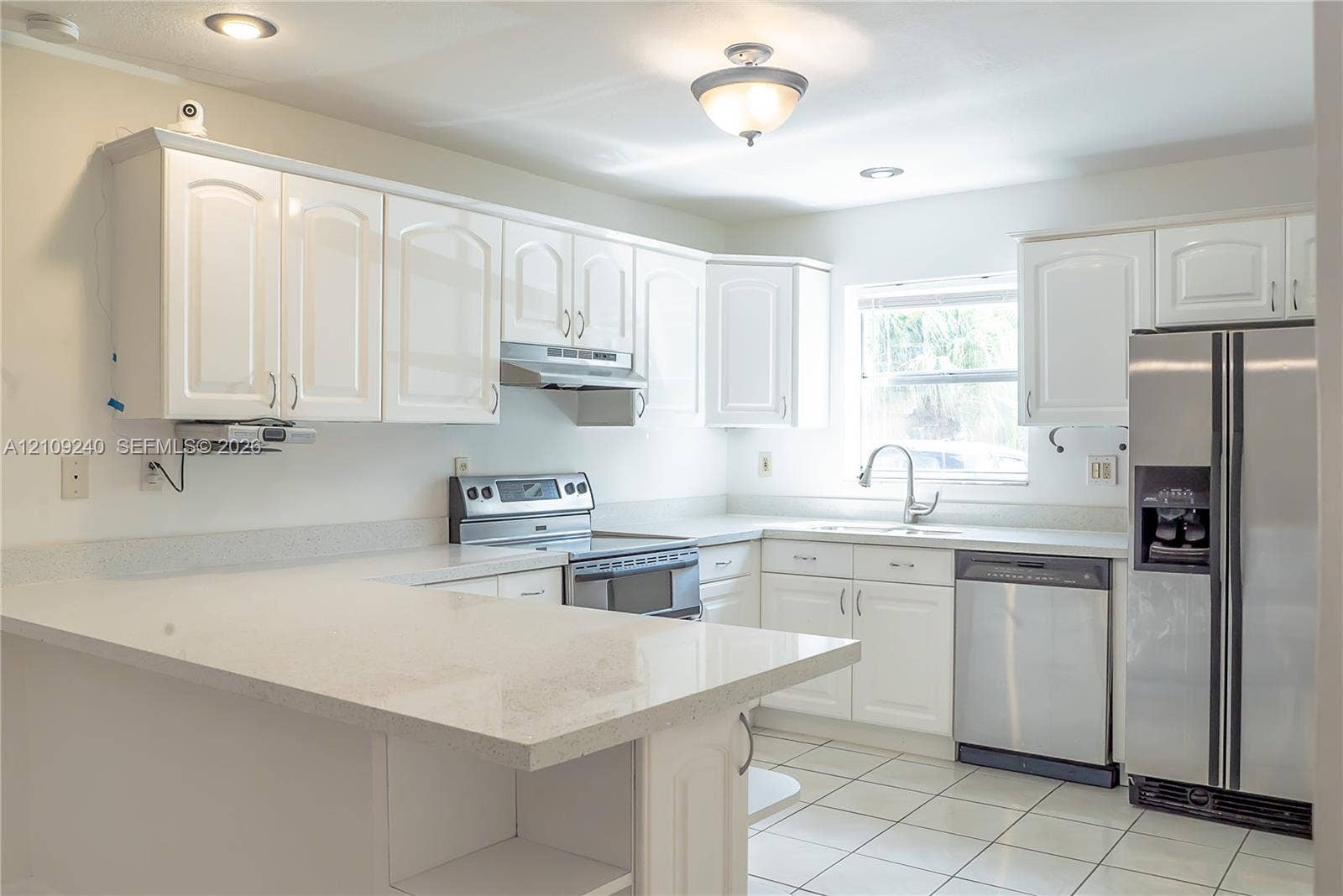 21115 SW 125th Ct Road, Miami, Miami, FL 33177 Kitchen featuring white cabinetry, solid-surface countertops with a breakfast bar, stainless steel appliances, and tile flooring