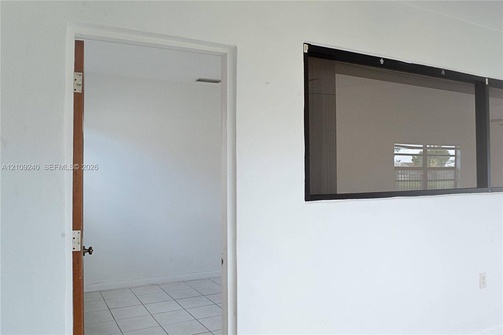 21115 SW 125th Ct Road, Miami, Miami, FL 33177 Interior space featuring light-colored tile flooring, a solid wood-finish door, and a horizontal window with a dark frame