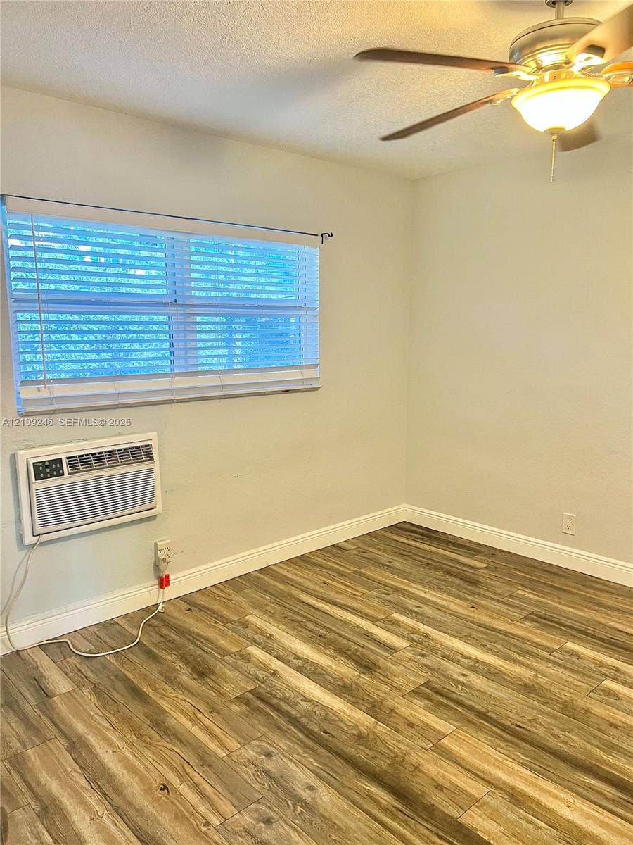 Room featuring wood-finish flooring, a ceiling fan with light fixture, and horizontal blind window treatments