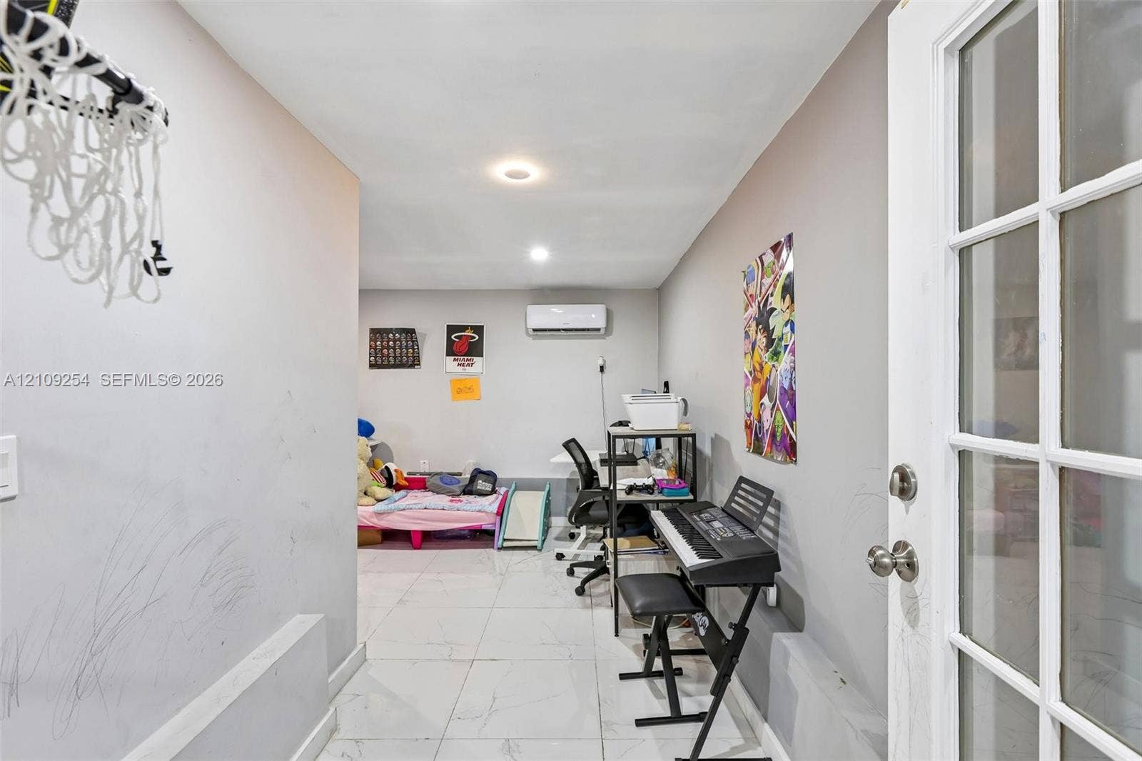 21342 NW 40th Cir Court, Miami Gardens, FL 33055 Interior room featuring large-format light-toned tile flooring, recessed lighting, and a wall-mounted ductless air conditioning unit, accessible via a glass-paneled entry door