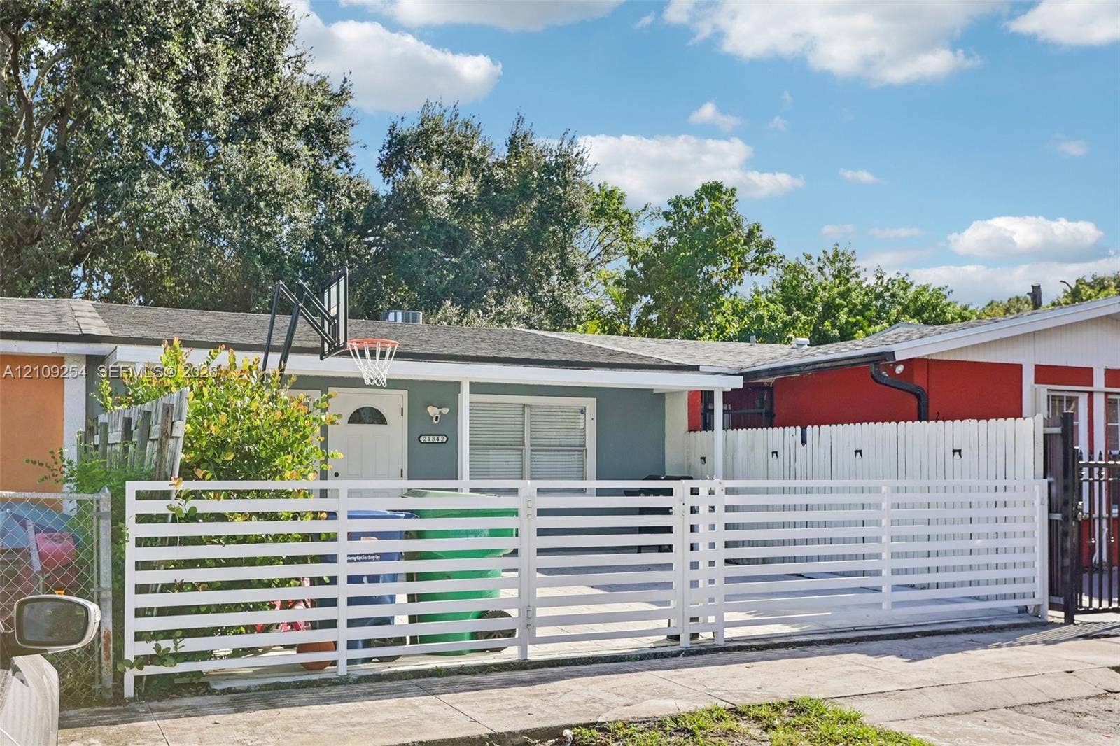 21342 NW 40th Cir Court, Miami Gardens, FL 33055 Single-story exterior featuring a horizontal slat privacy fence, concrete paved driveway, and mature landscaping
