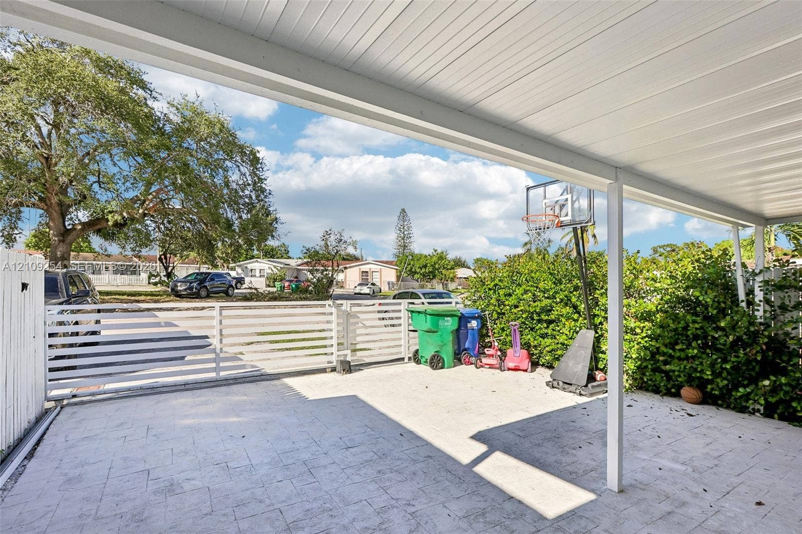 21342 NW 40th Cir Court, Miami Gardens, FL 33055 Covered patio featuring a paved surface and white horizontal-slat perimeter fencing