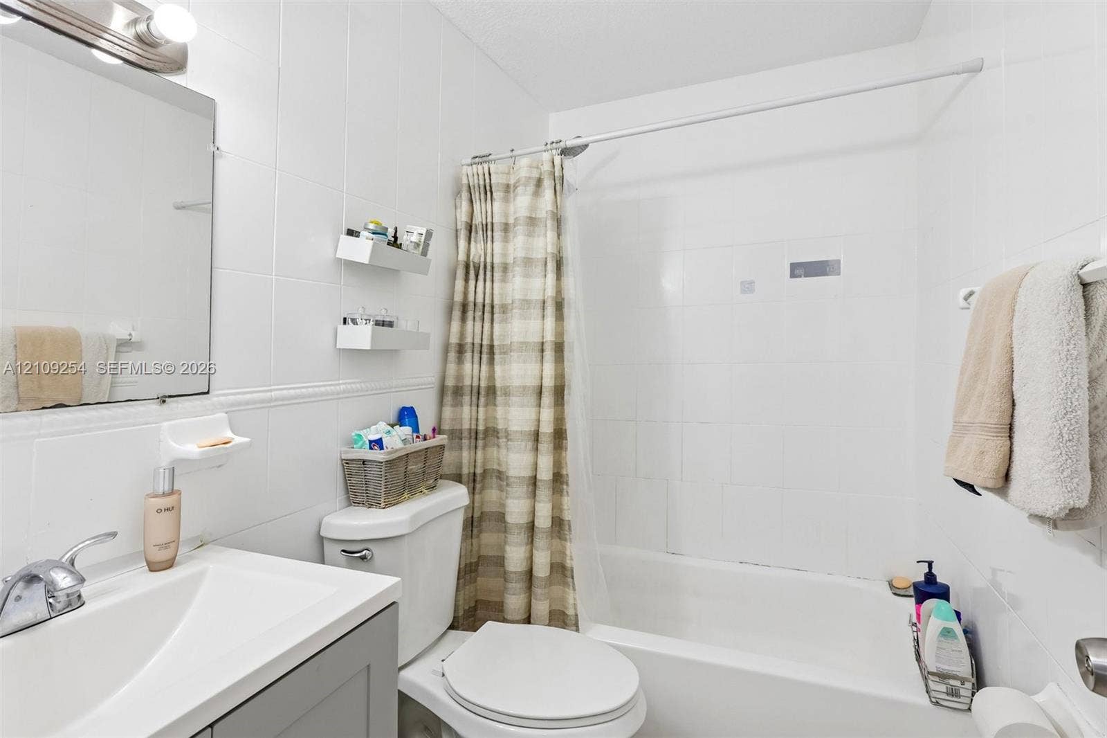 21342 NW 40th Cir Court, Miami Gardens, FL 33055 Bathroom featuring a vanity with an integrated sink, polished chrome faucet, white tile wall surround, built-in wall shelving, and a combination tub and shower