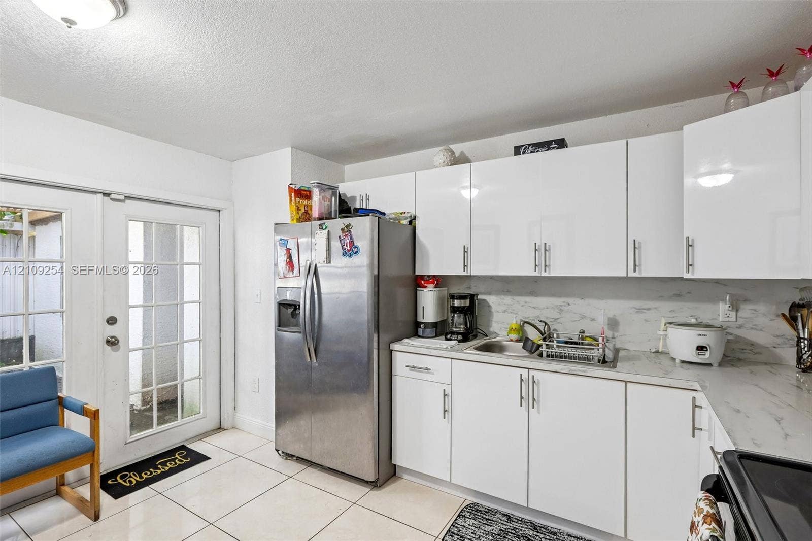 21342 NW 40th Cir Court, Miami Gardens, FL 33055 Kitchen featuring white slab-front cabinetry, stone-finish countertops, stainless steel side-by-side refrigerator, tile flooring, and glass-paneled exterior door