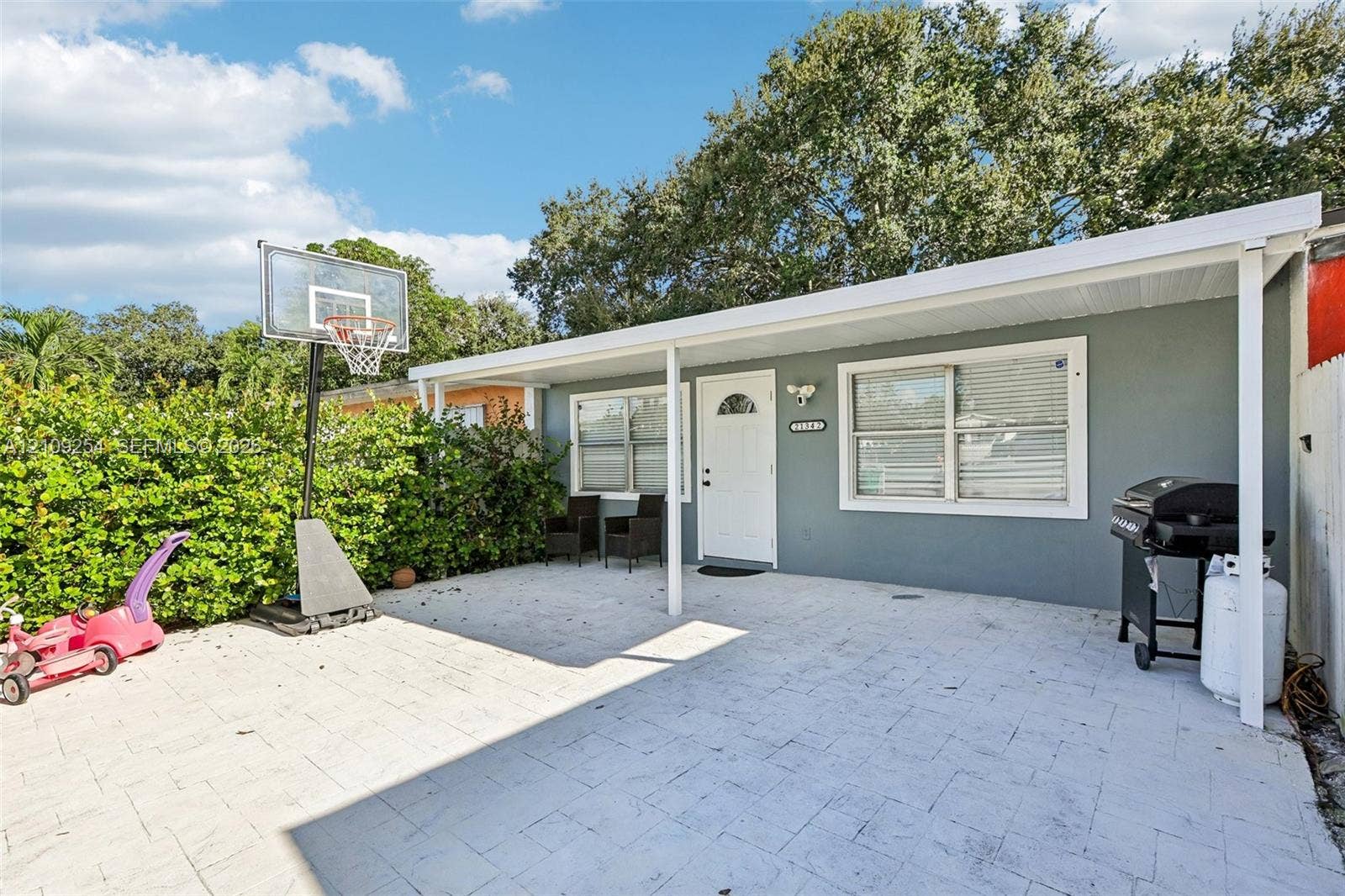 21342 NW 40th Cir Court, Miami Gardens, FL 33055 Covered patio featuring stone-paver flooring, light-colored exterior wall finish, and white-framed windows