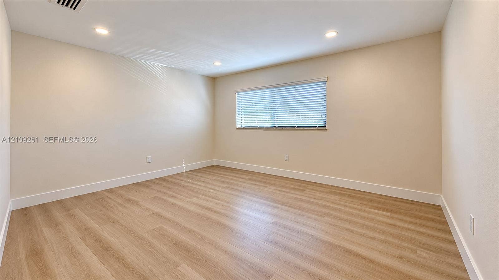 Neutral-toned interior featuring wood-finish flooring, recessed lighting, and horizontal window blinds