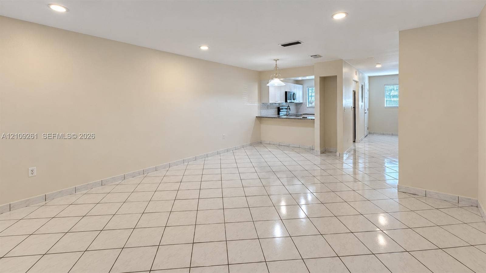 Open-concept interior featuring large-format diagonal tile flooring, recessed lighting, and a breakfast bar with stone-finish countertops
