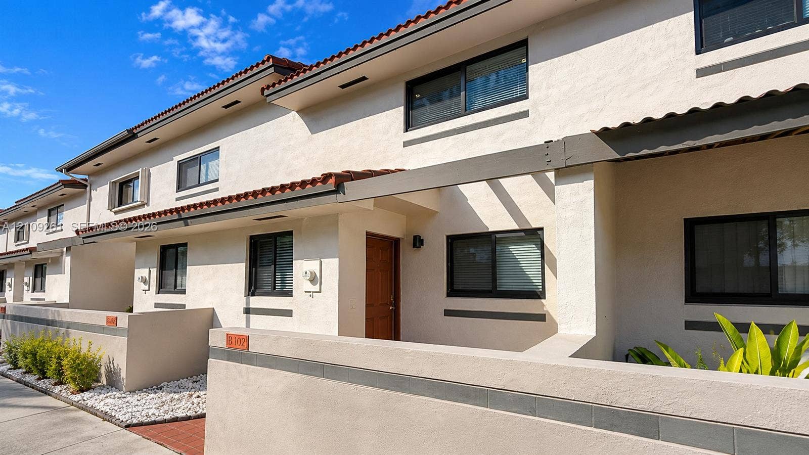 Stucco exterior with mission-style roof tiles, private courtyard walls, and integrated wooden structural accents
