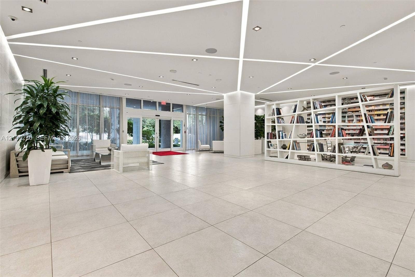 Large-format tile flooring, geometric ceiling lighting, and a floor-to-ceiling built-in open-shelf display unit