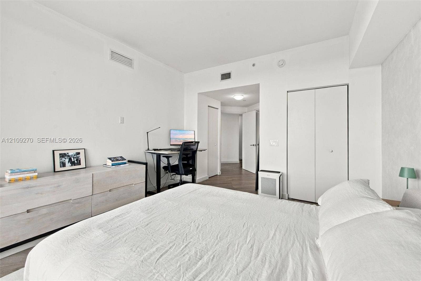 Room featuring wood-finish flooring, white walls, and a closet with double-panel doors