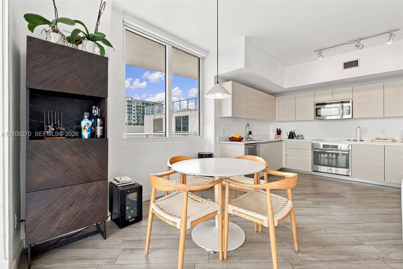 Modern kitchen featuring light-toned cabinetry, stainless steel appliances, wood-finish flooring, and track lighting