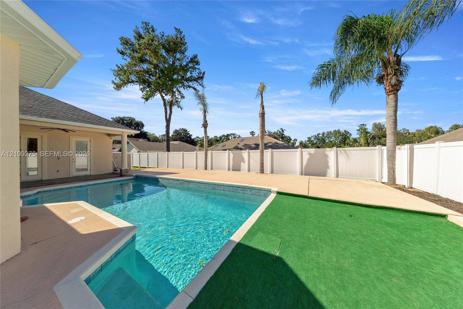 1035 SW 33rd Place, Ocala, FL 34471 Swimming pool with built-in stairs, expansive concrete decking, synthetic turf area, and privacy fencing