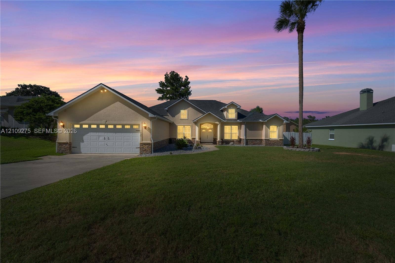1035 SW 33rd Place, Ocala, FL 34471 Single-story residence featuring a multi-gable roofline, stone veneer accents, an attached two-car garage, and a concrete driveway