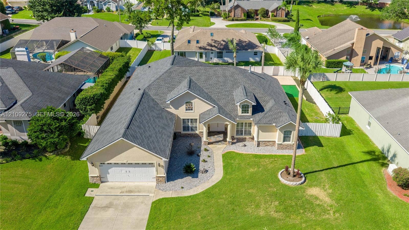 1035 SW 33rd Place, Ocala, FL 34471 Single-story residence featuring a multi-gable roofline, stone veneer accents, an attached two-car garage, and a concrete paver walkway