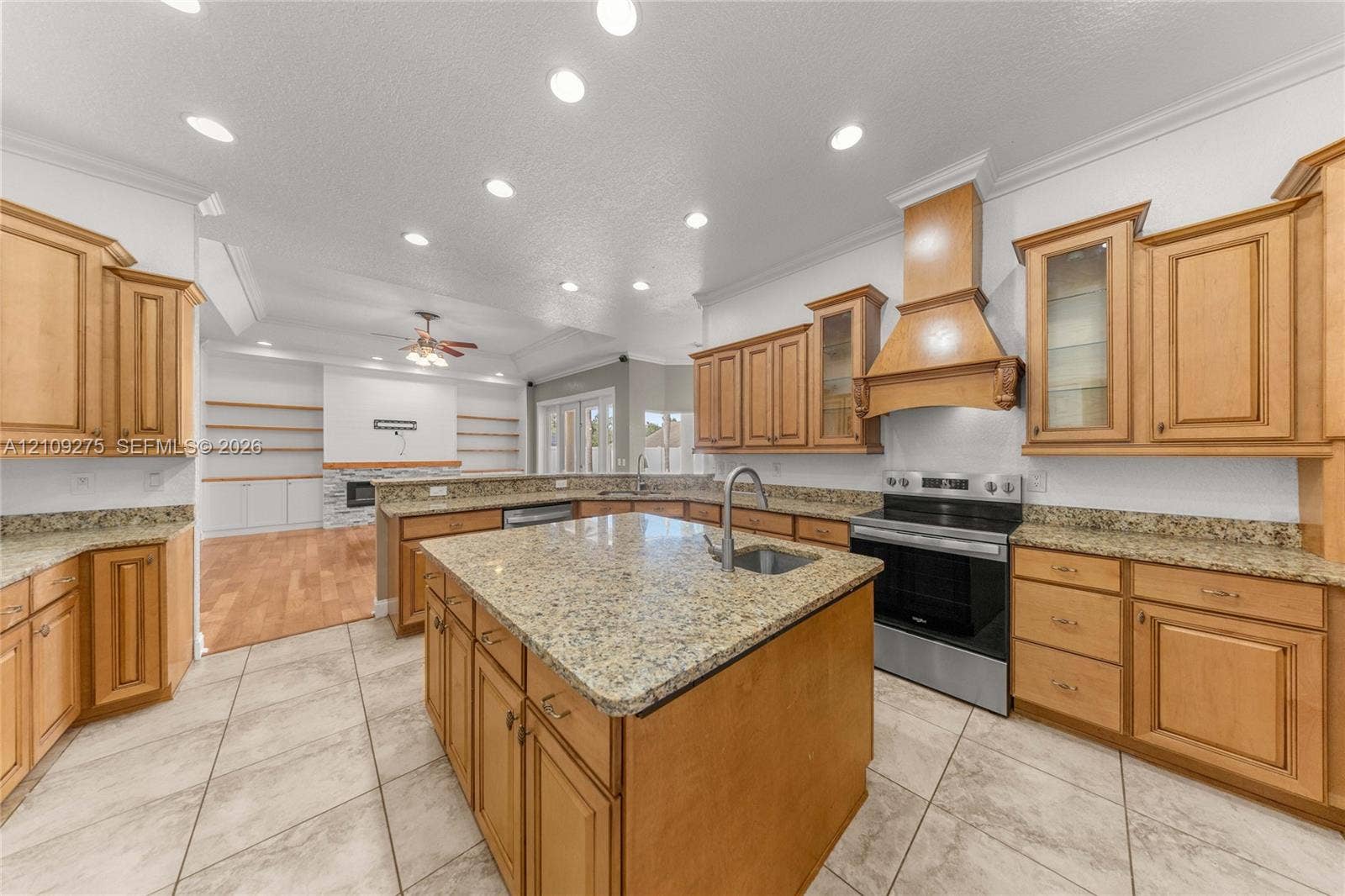 1035 SW 33rd Place, Ocala, FL 34471 Kitchen featuring wood cabinetry, stone countertops, a center island with an integrated sink, a custom wood range hood, and recessed lighting