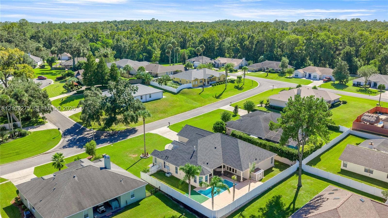 1035 SW 33rd Place, Ocala, FL 34471 Aerial view featuring a single-story residence with a multi-gabled roof, private swimming pool, concrete patio, and fenced perimeter