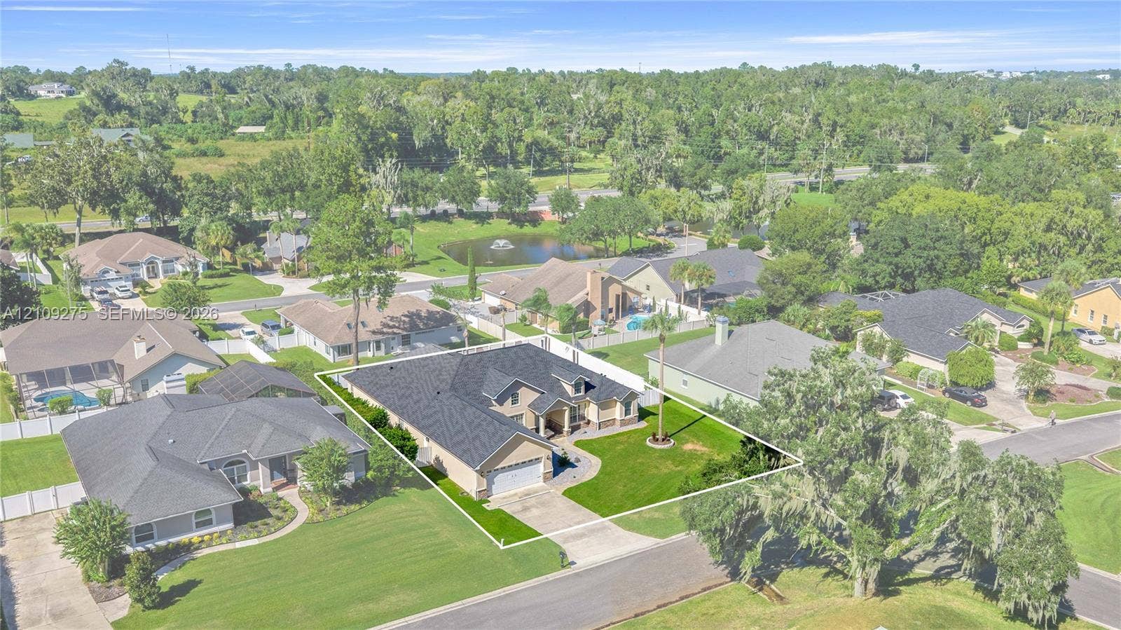 1035 SW 33rd Place, Ocala, FL 34471 Single-story residence featuring a multi-gabled shingle roof, a two-car garage, brick facade detailing, and a manicured front lawn