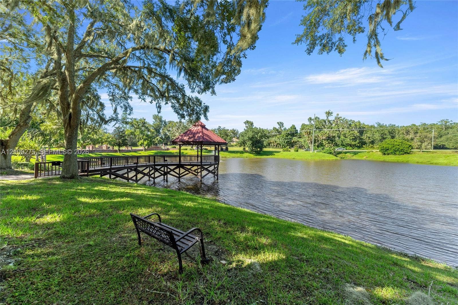 1035 SW 33rd Place, Ocala, FL 34471 Waterfront grounds featuring a wooden pier with a covered gazebo, expansive lawn, and mature oak trees