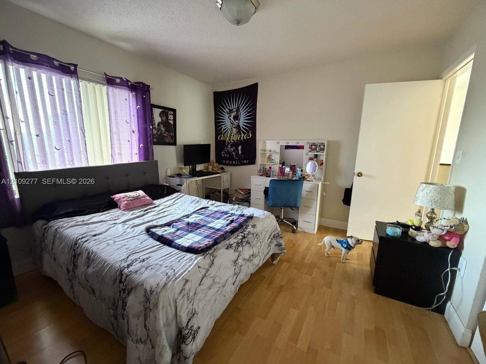 Bedroom featuring wood-finish flooring, a large window, and a flush-mount ceiling light fixture