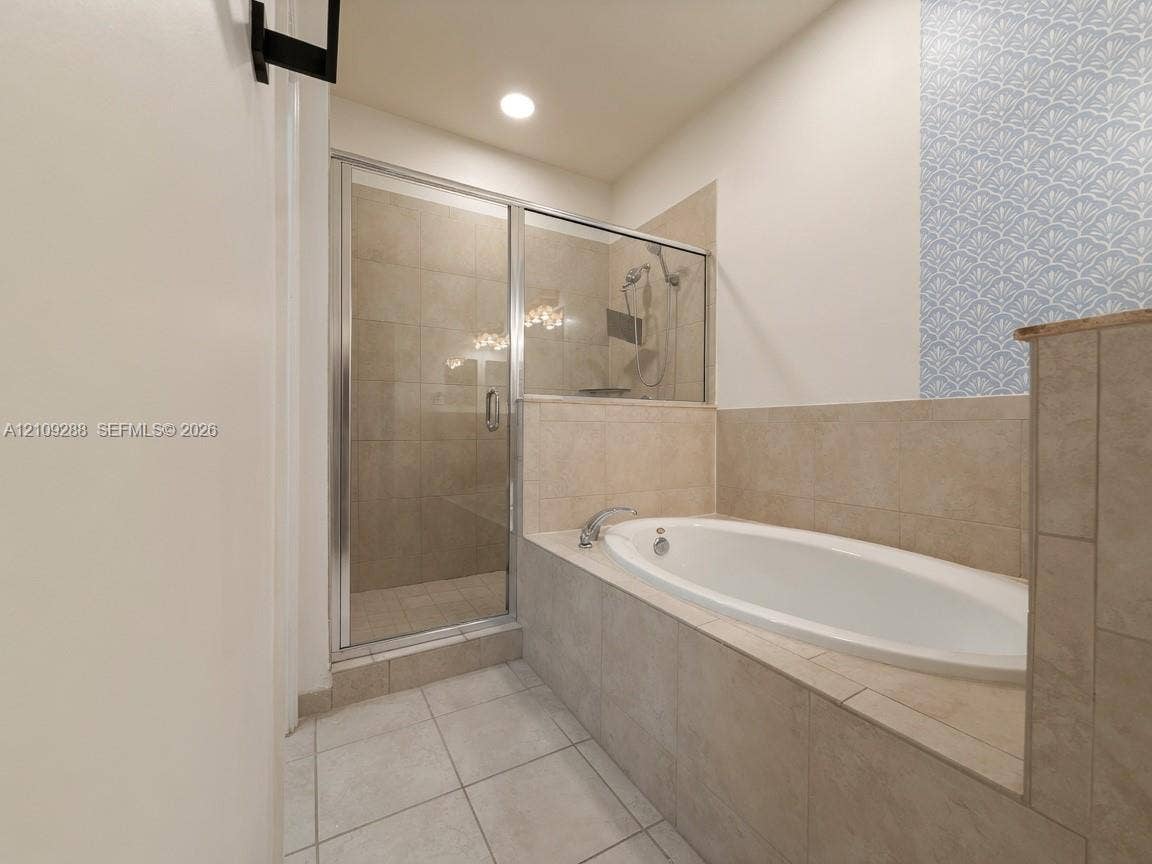 Built-in oval soaking tub with tile surround, glass-enclosed shower with tiled interior, and decorative patterned tile wall accent