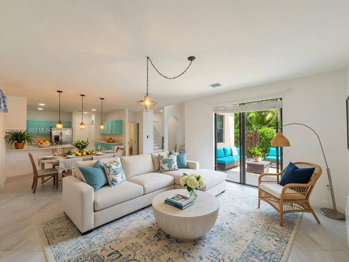 Open-concept living space featuring large-format tile flooring, a hanging geometric pendant light, kitchen cabinetry, and sliding glass doors