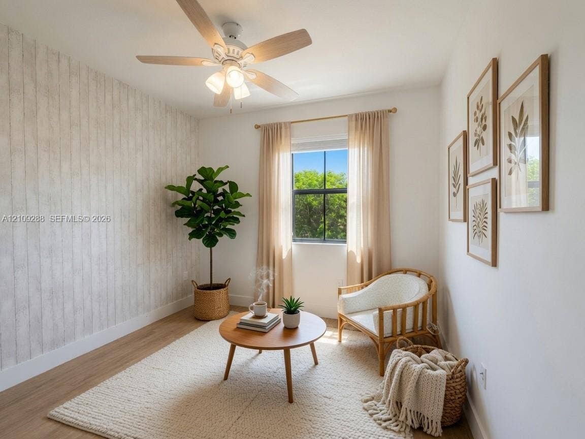 Room featuring wood-finish flooring, a textured vertical-plank accent wall, and a multi-blade ceiling fan with integrated lighting