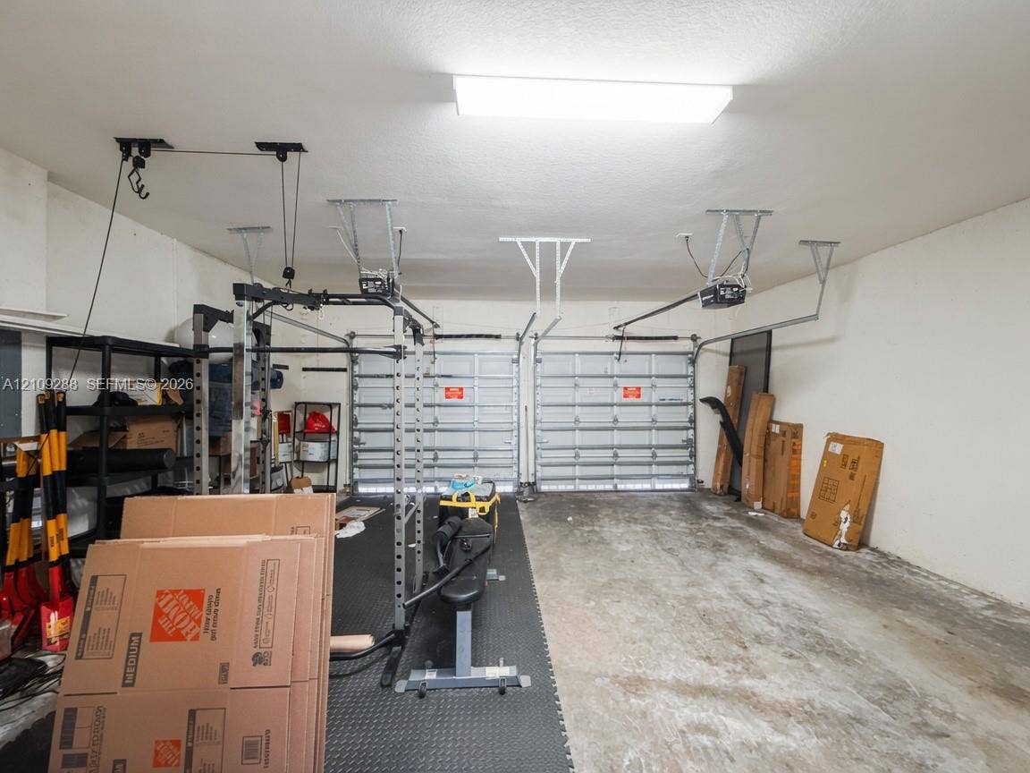 Two-car garage featuring dual sectional overhead doors, concrete flooring, and ceiling-mounted automatic door openers