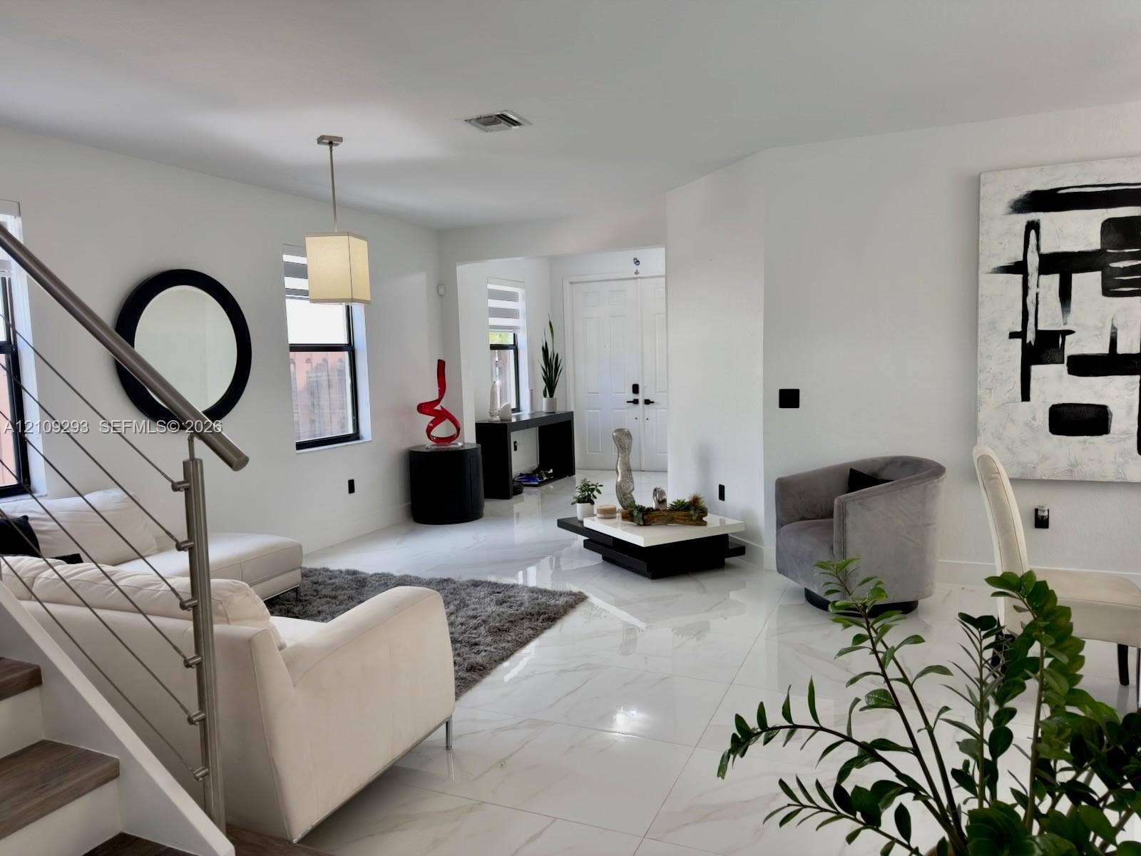8880 NW 115th Court, Doral, FL 33178 Open-concept interior featuring large-format tile flooring, metal cable railing, and double-door entryway