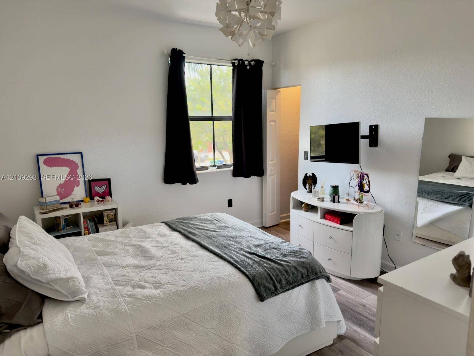 8880 NW 115th Court, Doral, FL 33178 Room featuring wood-finish flooring, a multi-pane window, and a modern geometric pendant light fixture