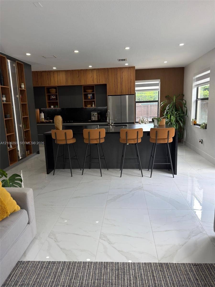 8880 NW 115th Court, Doral, FL 33178 Kitchen featuring a center island, matte dark cabinetry with wood-finish upper detailing, recessed lighting, and large-format porcelain tile flooring