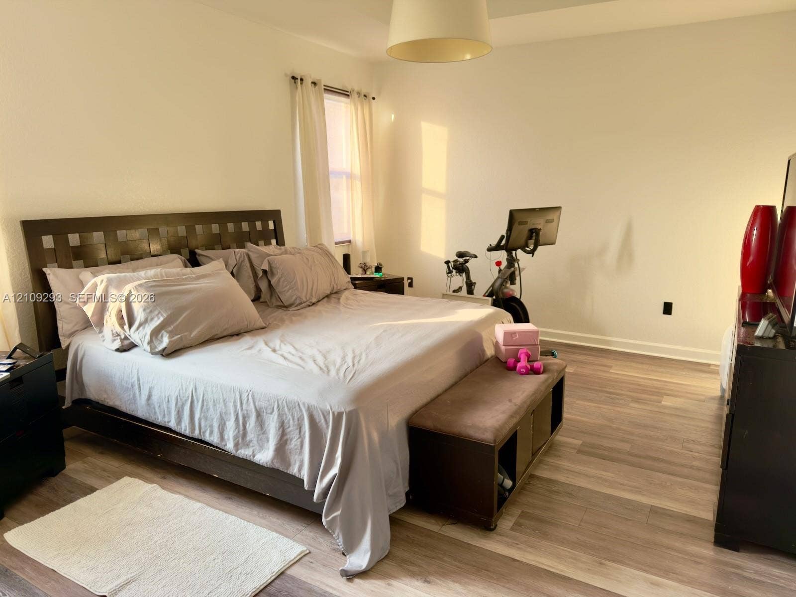 8880 NW 115th Court, Doral, FL 33178 Room featuring wood-finish flooring, a recessed tray ceiling, and a central pendant light fixture