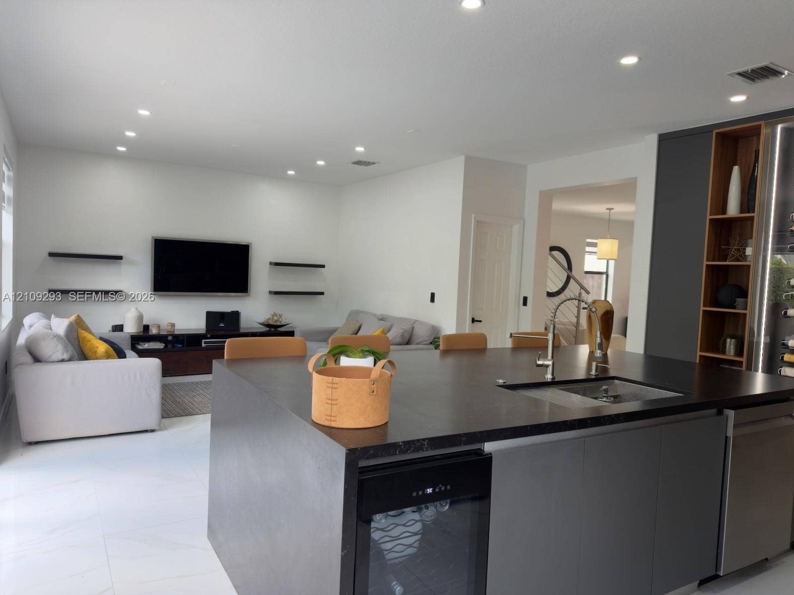 8880 NW 115th Court, Doral, FL 33178 Large kitchen island featuring a dark stone countertop, undermount sink, integrated wine cooler, and flat-panel cabinetry