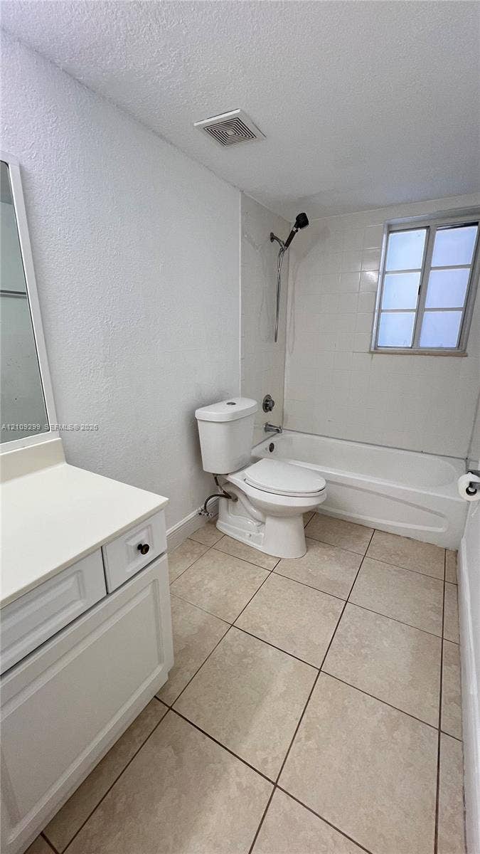 4810 NW 79 Avenue, #107, Doral, Doral, FL 33166 Bathroom featuring square tile flooring, a white vanity cabinet with a solid surface countertop, and a tub-shower combination with full-height wall tile