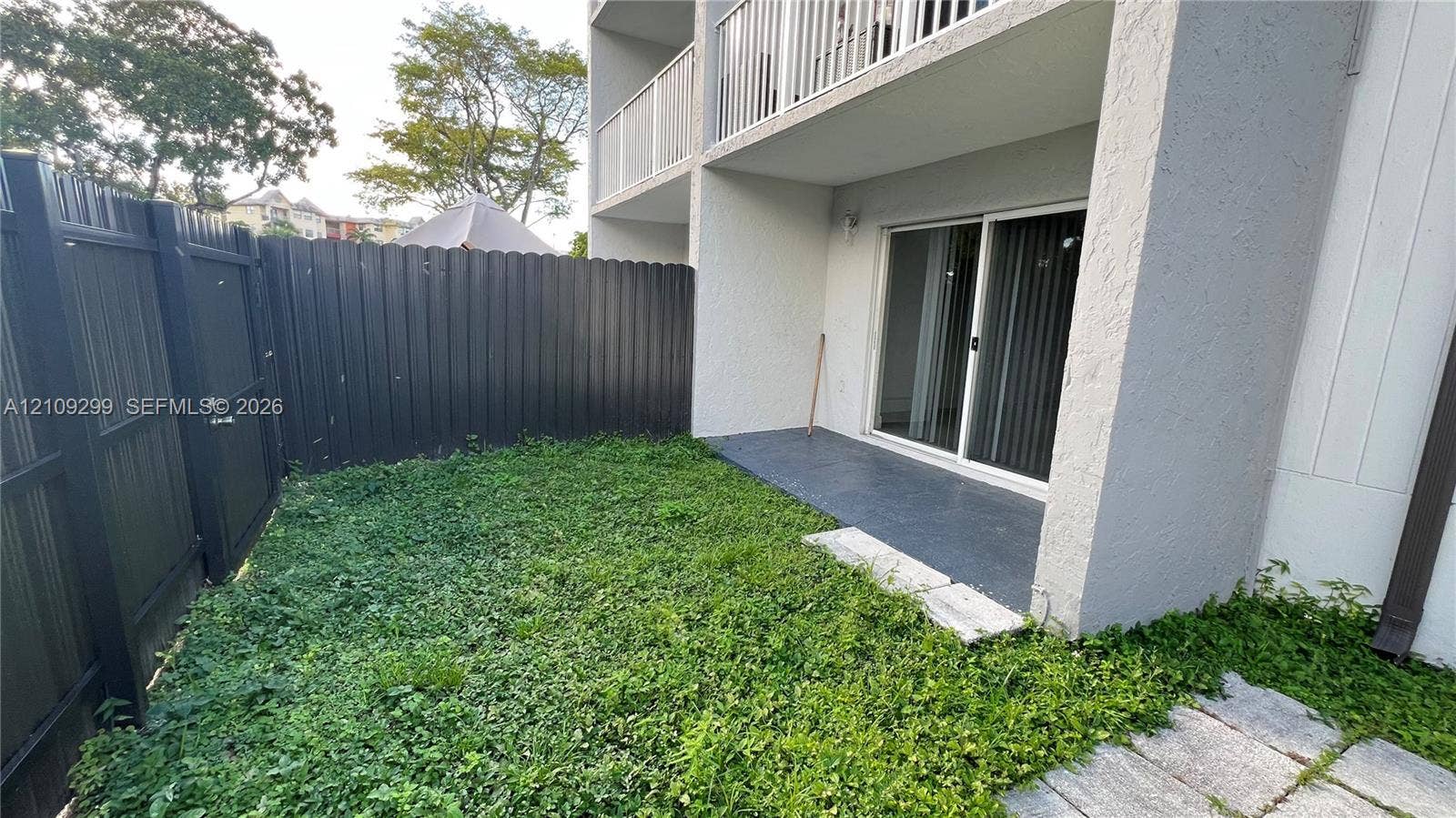4810 NW 79 Avenue, #107, Doral, Doral, FL 33166 Private fenced-in outdoor space featuring a concrete patio, grassy yard area, and a sliding glass door entry