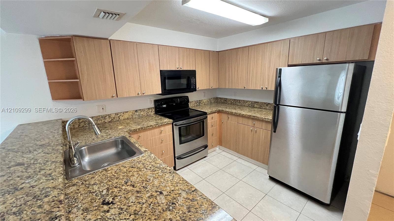 4810 NW 79 Avenue, #107, Doral, Doral, FL 33166 Kitchen featuring light-finish cabinetry, stone-surface countertops, stainless steel appliances, ceramic tile flooring, and a single-basin undermount sink with a high-arch faucet