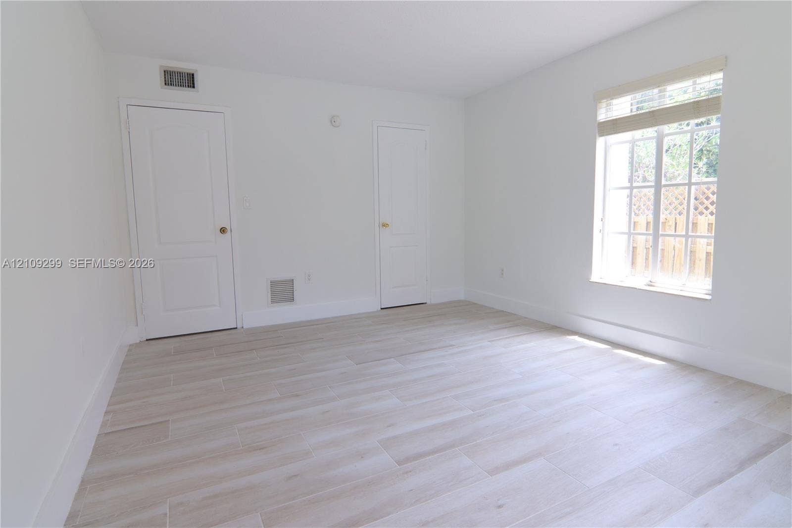 4810 NW 79 Avenue, #107, Doral, Doral, FL 33166 Neutral interior space featuring wood-finish tile flooring, multi-pane window with blinds, and two solid-core interior doors