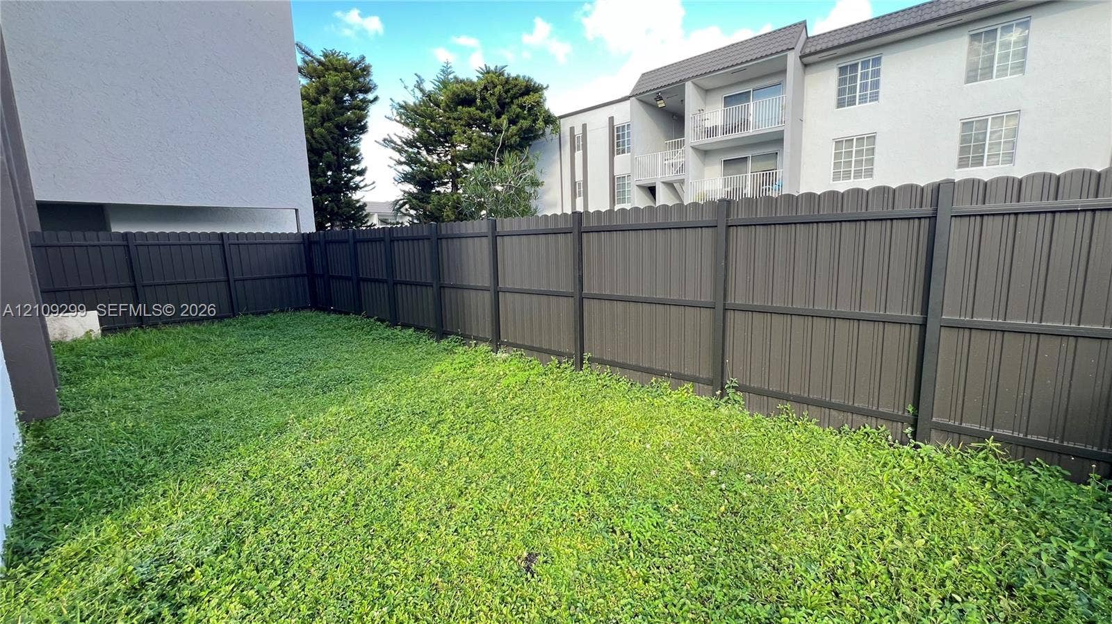 4810 NW 79 Avenue, #107, Doral, Doral, FL 33166 Private outdoor space featuring a dark-toned vertical slat privacy fence and a grassy yard