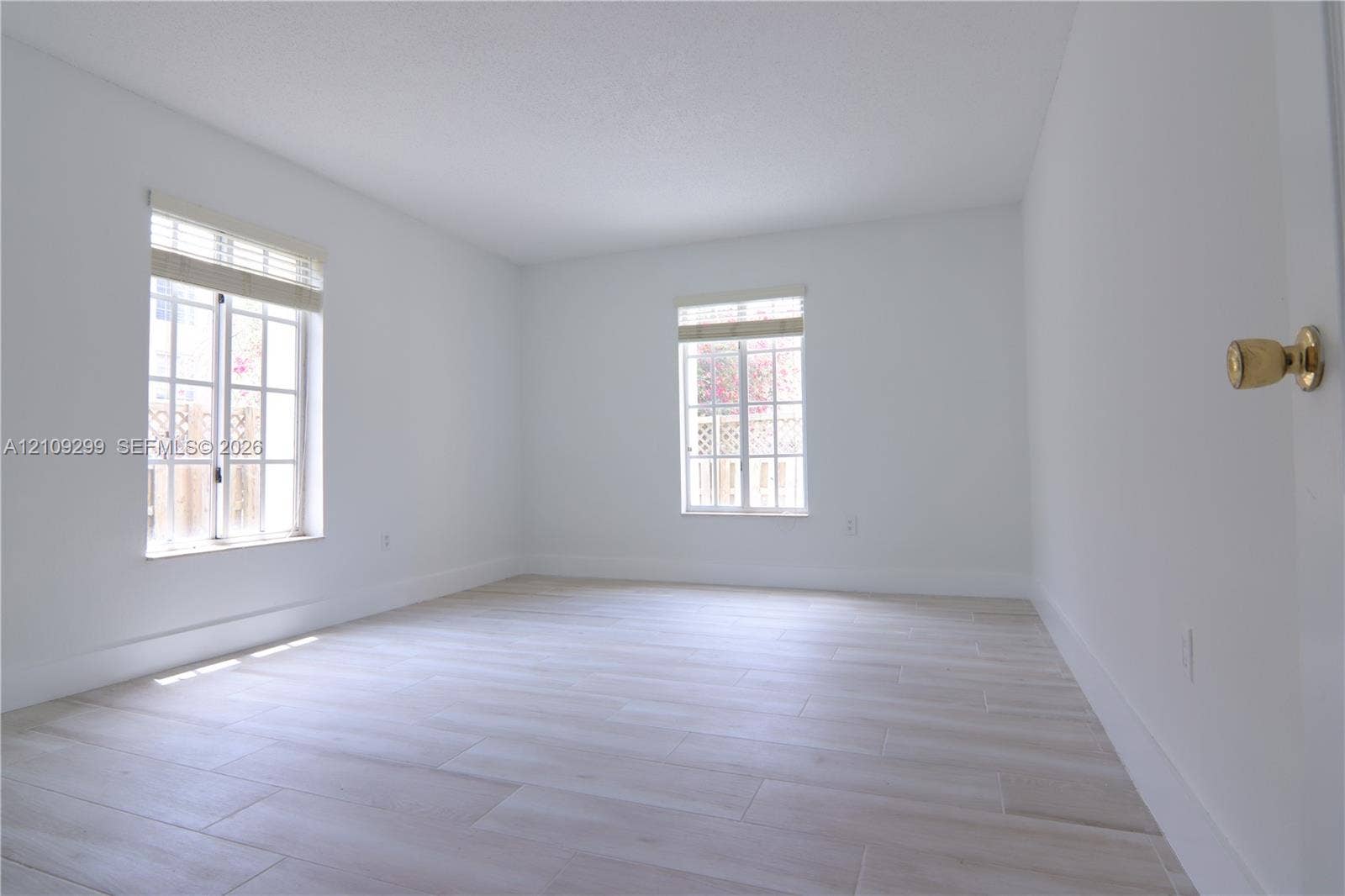 4810 NW 79 Avenue, #107, Doral, Doral, FL 33166 Interior room featuring neutral wall finishes, wood-finish flooring, and two windows with integrated grid patterns