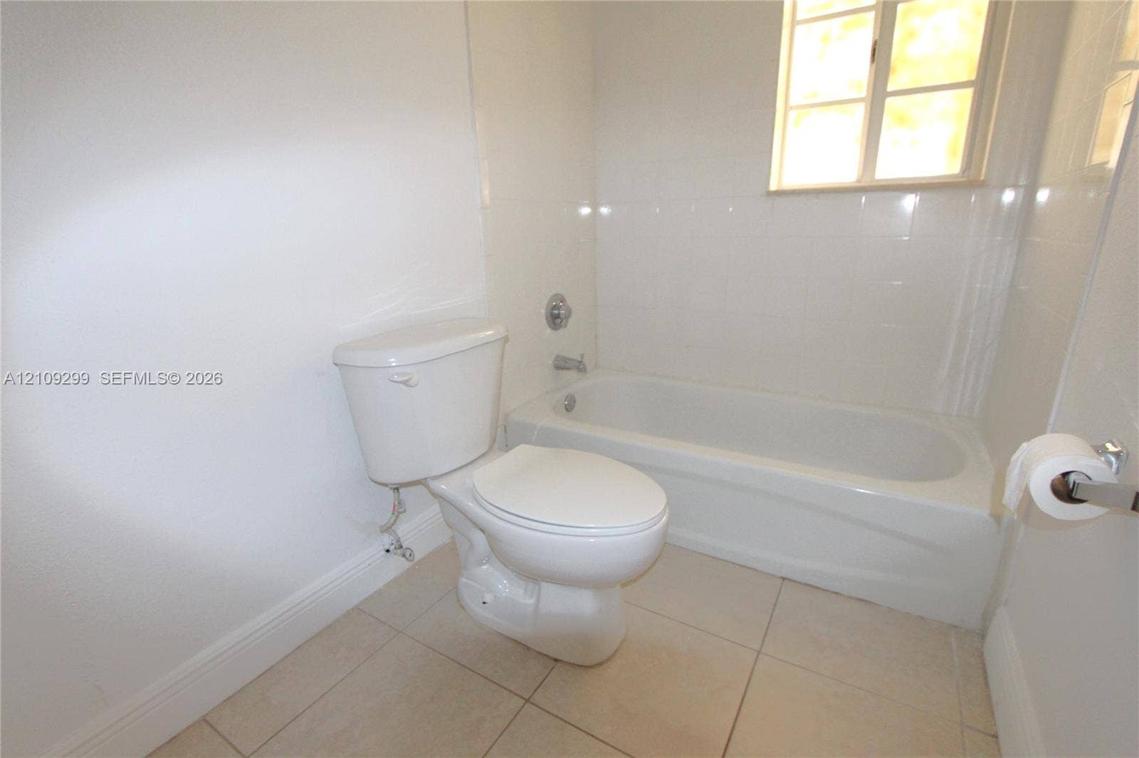 4810 NW 79 Avenue, #107, Doral, Doral, FL 33166 Full bathroom featuring a white porcelain toilet, integrated bathtub and shower combination with tile surround, and neutral-toned floor tile