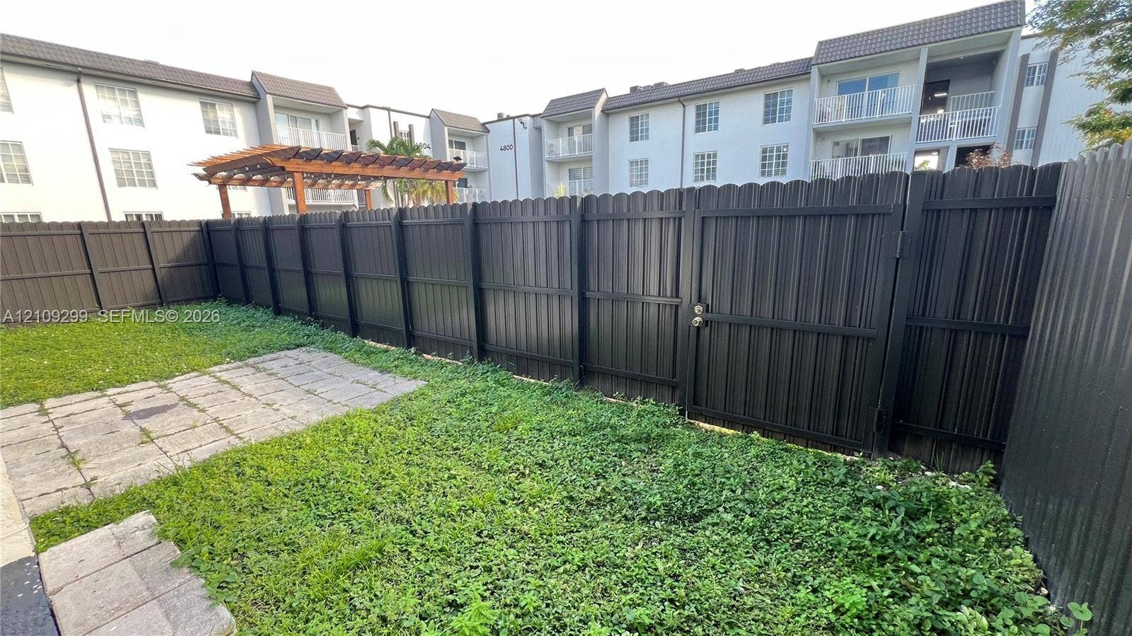 4810 NW 79 Avenue, #107, Doral, Doral, FL 33166 Private outdoor space featuring a dark-toned privacy fence, a gated entry, and a paved patio surface