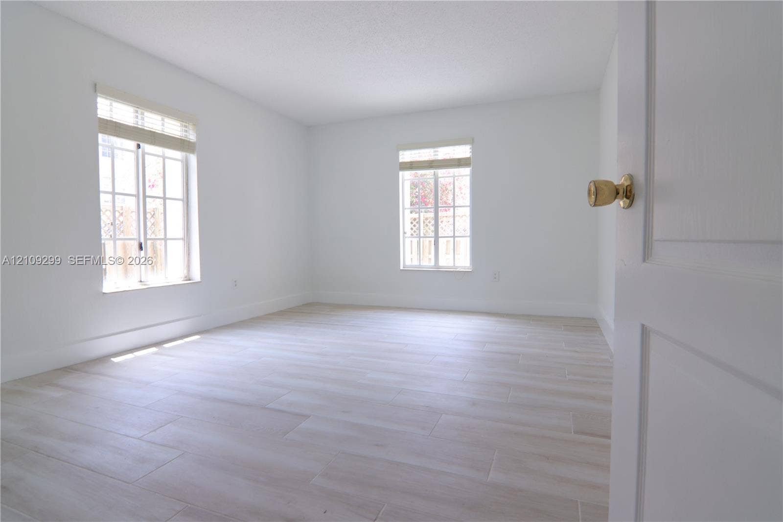 4810 NW 79 Avenue, #107, Doral, Doral, FL 33166 Neutral-toned wood-finish flooring, two multi-pane windows with integrated blinds, and a solid-core interior door with polished brass hardware
