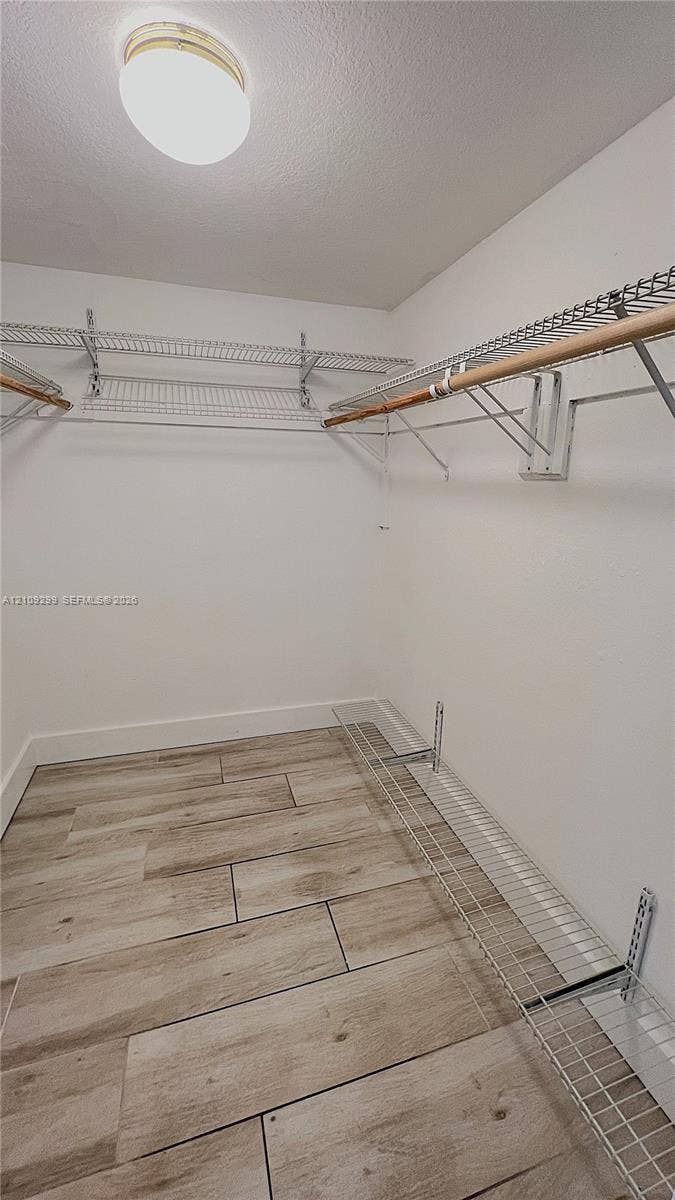 4810 NW 79 Avenue, #107, Doral, Doral, FL 33166 Walk-in closet featuring wood-finish tile flooring, multi-level wire shelving, integrated hanging rods, and a ceiling-mounted light fixture
