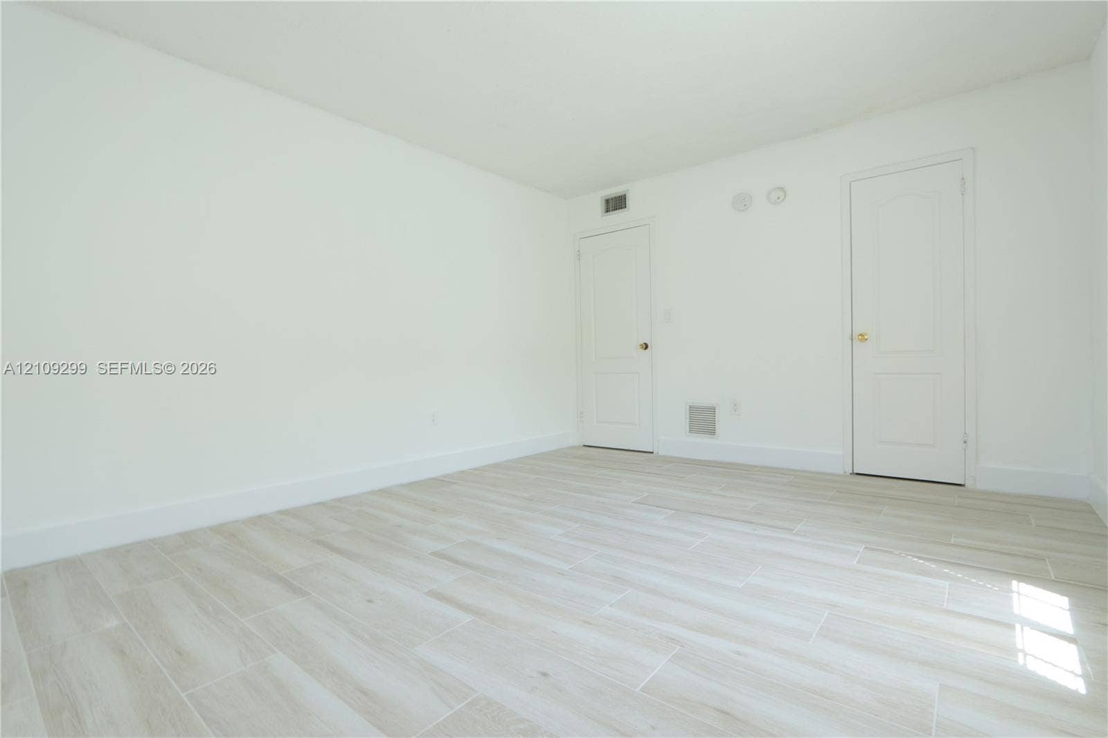 4810 NW 79 Avenue, #107, Doral, Doral, FL 33166 Interior space featuring neutral wall paint, wood-finish tile flooring, and two interior doors with brass hardware