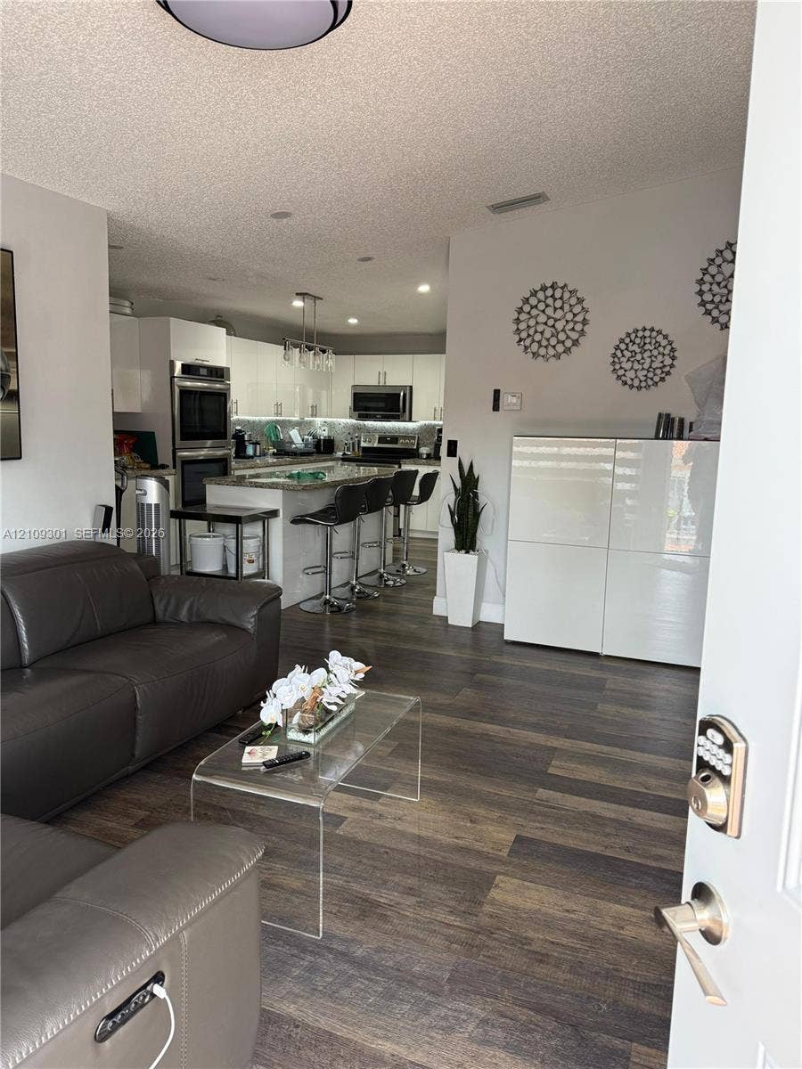 7680 SW 153rd Court, #204, Miami, Miami, FL 33193 Kitchen featuring white flat-panel cabinetry, stone-finish countertops, built-in wall oven, and recessed lighting, with wood-finish flooring throughout