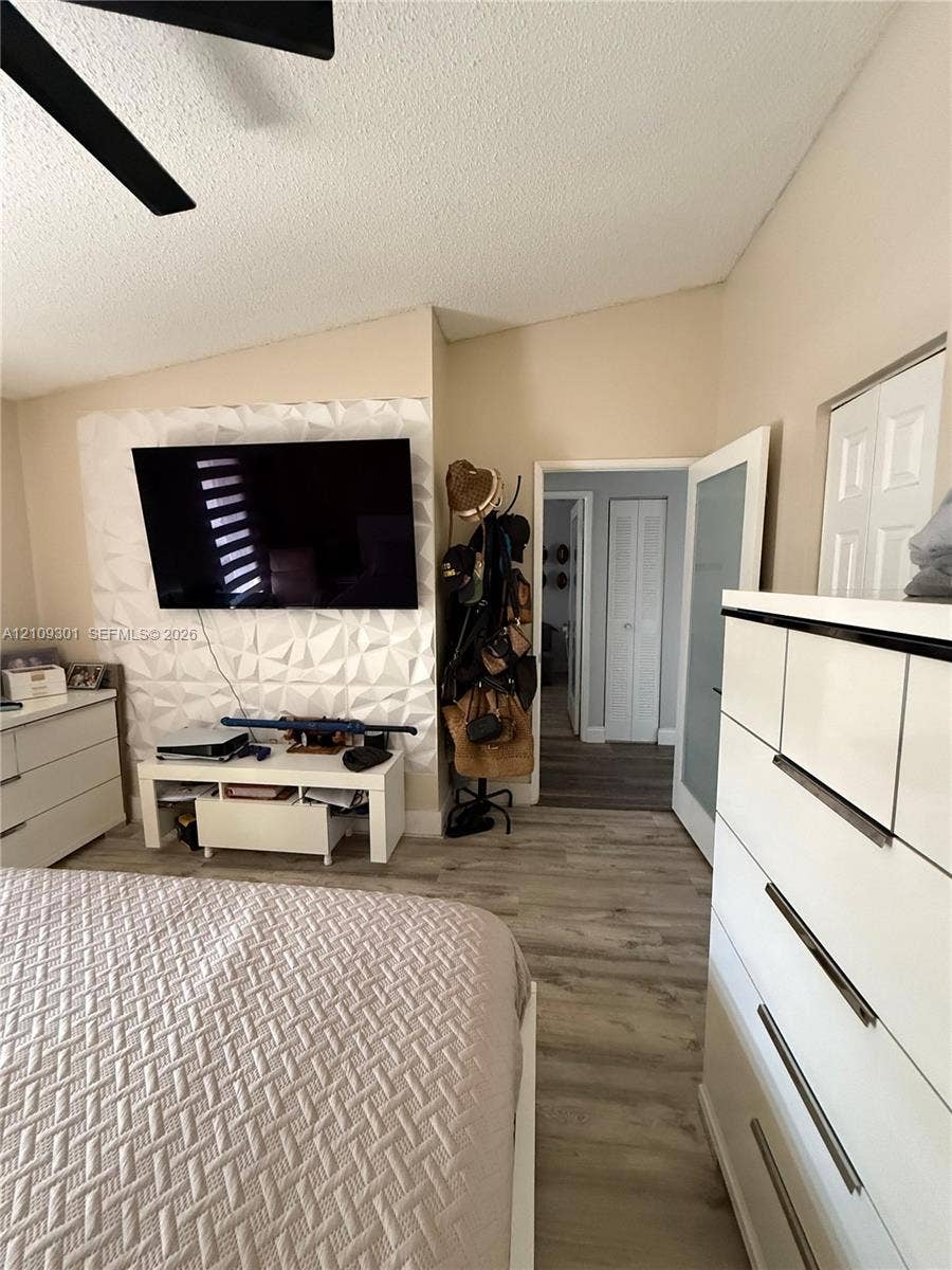 7680 SW 153rd Court, #204, Miami, Miami, FL 33193 Vaulted ceiling with a central fan, textured three-dimensional wall paneling, and wood-finish flooring